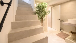 Un escalier moderne au design minimaliste, menant à un espace salle de bain comprenant un lavabo et une plante.