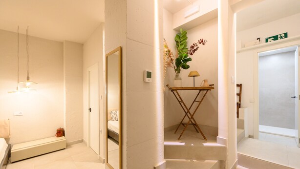 Une chambre d’hôtel avec un lit, une table de chevet, une lampe et une petite plante.