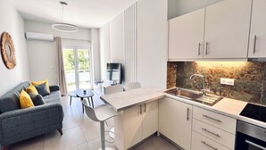 A modern kitchen with white cabinets, a marble countertop, and a built-in oven. - Downtown Bliss – Piraeus Street by ΜΡS (Athina)