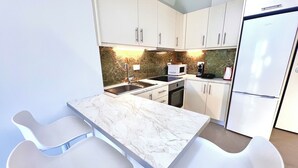 A modern kitchen with white cabinets, a marble countertop, and a built-in oven. - Downtown Bliss – Piraeus Street by ΜΡS (Athina)