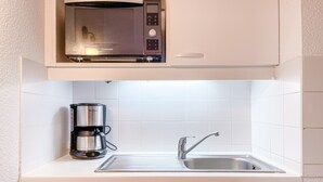 A kitchen with a microwave, coffee maker, sink, and dishwasher.