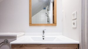 A bathroom with a white sink, wooden vanity, and a mirror.