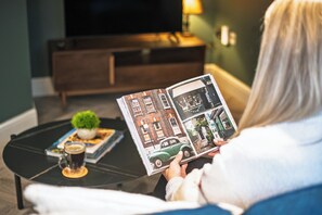 A person reading a magazine on a black coffee table with a small plant and a cup of coffee. - The Fox Pub & Inn (London)