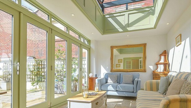 A living room with a sofa, a small table, and a large window with a view of a brick building.