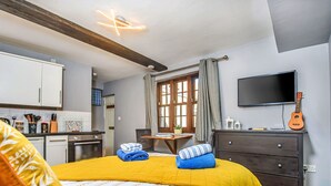 Une chambre d’hôtel avec un lit, un bureau, une télévision et une guitare.