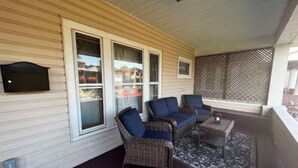 Une véranda aménagée avec des meubles en osier, une petite table et un paravent décoratif.
