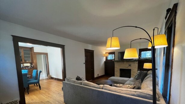 Un salon avec un canapé gris, un plancher en bois et un coin repas agrémenté d’une chaise bleue.