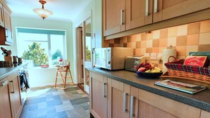 Una cocina moderna con armarios de madera, microondas, tostadora y un bol de fruta en la encimera.