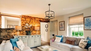 A living room with a stone wall, a sofa set, a coffee table, and a chandelier.