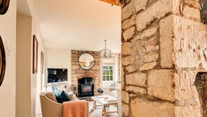 A cozy living room with a stone fireplace, a sofa, and a television.