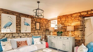A cozy living room with a stone wall, a sofa set, a coffee table, and a cabinet with lamps.