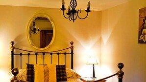 Un lit avec un cadre en métal, un miroir rond au-dessus et un lustre.
