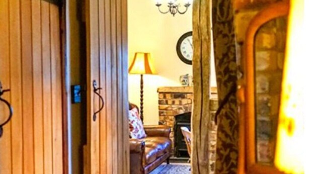 Une pièce chaleureuse avec une porte en bois, une cheminée, un canapé et une lampe.