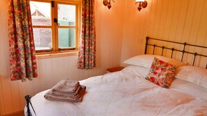 Een slaapkamer met een bed, bloemen gordijnen, een raam en wandlampen.