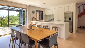 A modern kitchen with a large island, white cabinets, and a stainless steel refrigerator.