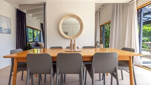 A modern dining area with a wooden table, grey chairs, and a large mirror on the wall.