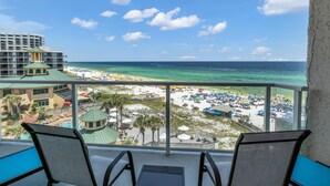Un balcón con vista a una playa, una zona de piscina y un edificio de hotel.