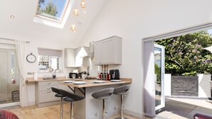 A modern kitchen with a central island, bar stools, and a dining area with red leather chairs.