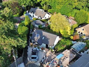 An aerial view of a residential area with multiple houses, a driveway, and a car parked in front of one of the houses.