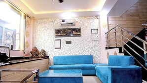 A modern lobby with a blue sofa, a coffee table, and a staircase. - Hotel Akash Inn  Hotel Near Taj Mahal (Agra)