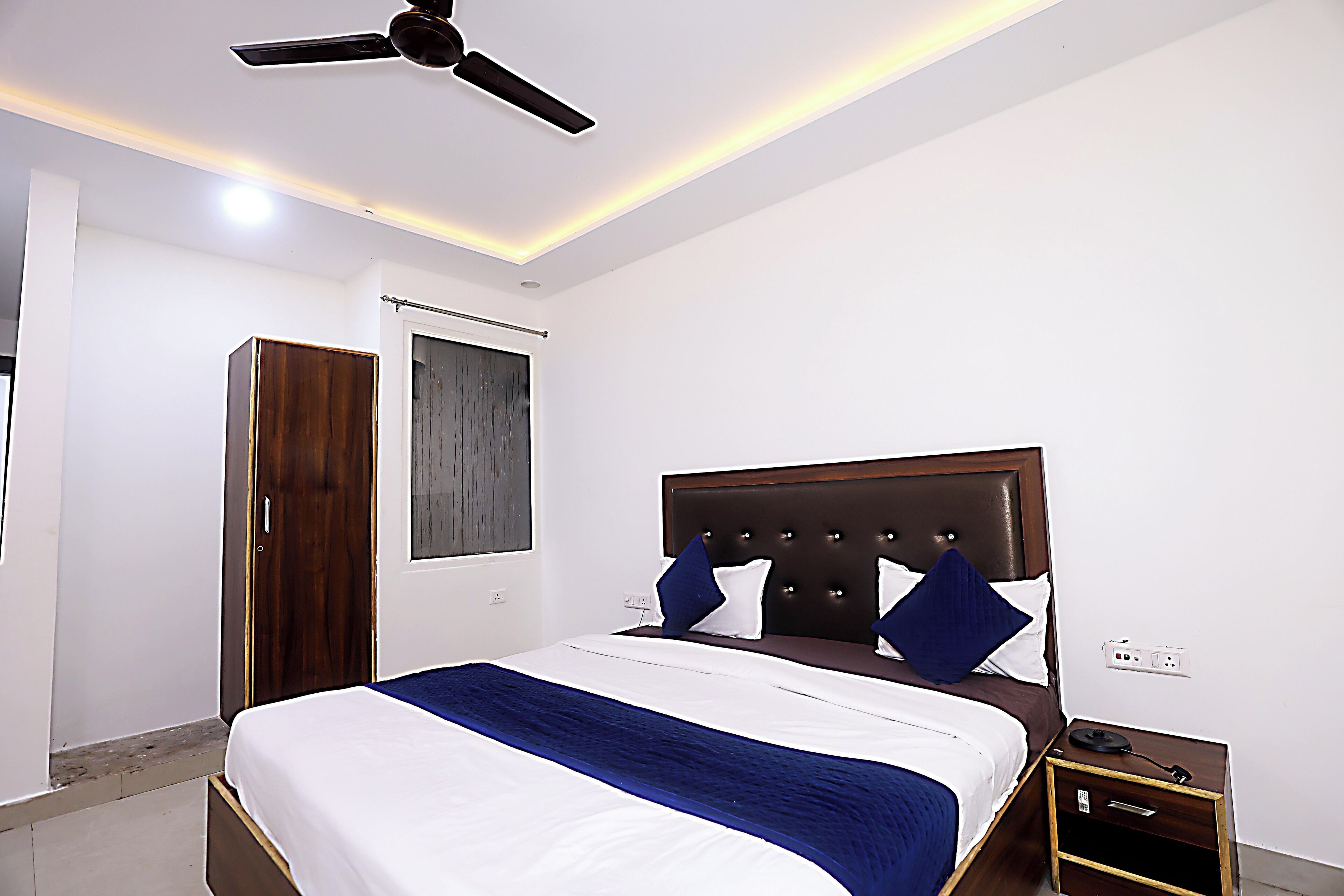 Ein Schlafzimmer mit Bett, Kleiderschrank, Deckenventilator und Fenster.