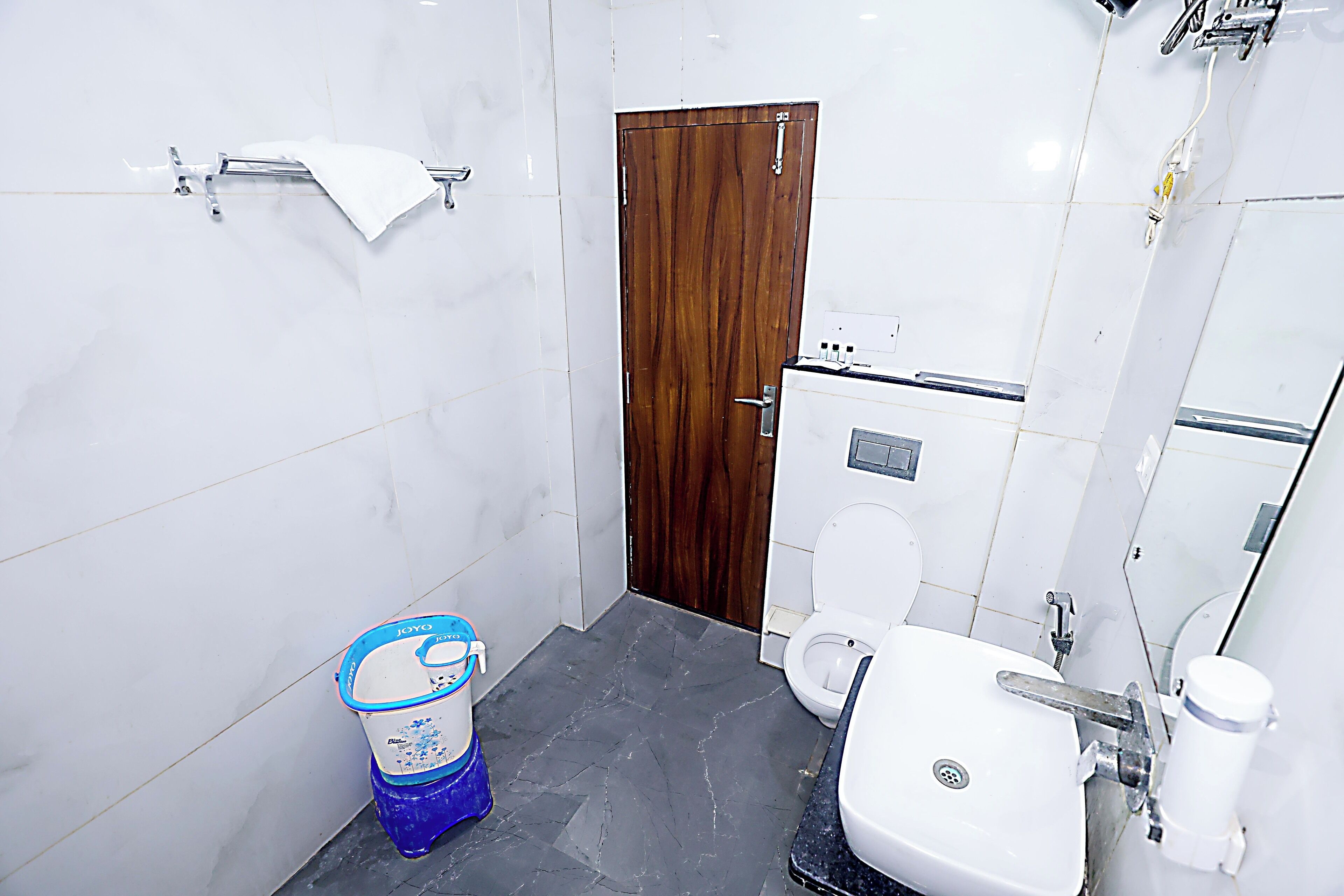 Une salle de bain avec des toilettes, un lavabo et un grand seau bleu.