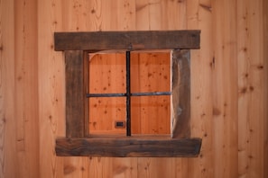 Una ventana de madera rústica con un diseño sencillo, en una pared de madera.