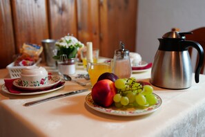Una mesa de desayuno con un plato de fruta, una cafetera y un vaso de jugo de naranja.