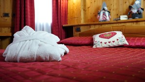 A bed with a red quilt and a white fluffy pillow. - Hotel Cime Bianche (Valtournenche)