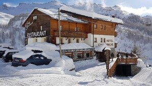 A wooden building with a restaurant and hotel signs, surrounded by snow-covered mountains. - Hotel Cime Bianche (Valtournenche)