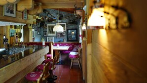 A rustic wooden interior with a bar area, wooden benches, and a stone wall. - Hotel Cime Bianche (Valtournenche)