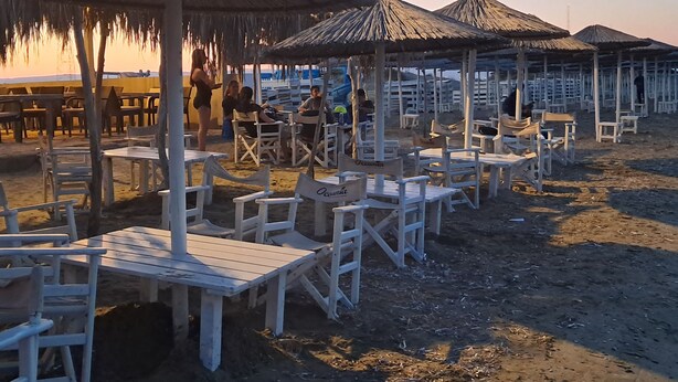 Mobiliario exterior con mesas y sillas bajo sombrillas de paja.