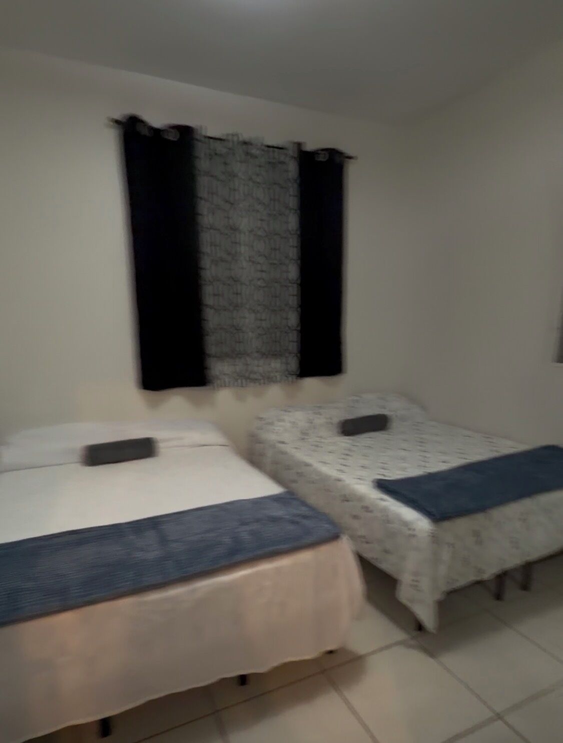 A room with two beds, each with a pillow and a blanket.