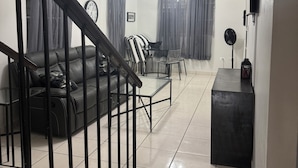Una sala de estar moderna con una escalera, un sofá, una mesa de centro y un comedor.