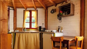 Een compacte keuken met houten kastjes, een kleine eettafel en een raam met geruit gordijnen.