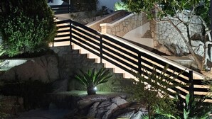 A modern staircase with a wooden railing leading up to a stone wall.