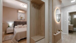 A modern bedroom with a bed, bedside table, lamp, and a decorative wall piece.