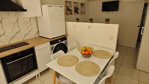 Une cuisine compacte équipée d’un four encastré, d’un lave-linge et d’un coin repas avec une table pour quatre personnes.
