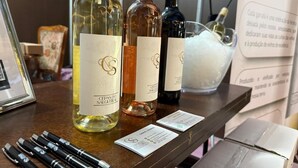 A selection of wine bottles on a wooden table with a framed picture and pens.