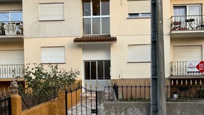 A two-story building with a tiled roof, a gated entrance, and a small garden area.