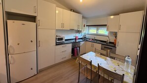 A compact kitchen with white cabinets, a microwave, a sink, and a dining table with chairs.