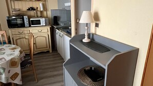 Una cocina compacta con microondas, horno y una pequeña mesa de comedor con sillas.
