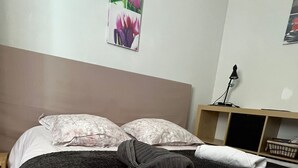 Una cama bien tendida con ropa de cama floral, un cabecero y una mesita de noche con una lámpara.