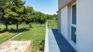A modern building with a metal fence, a paved walkway, and a grassy area with trees. - Appia (Mestre)