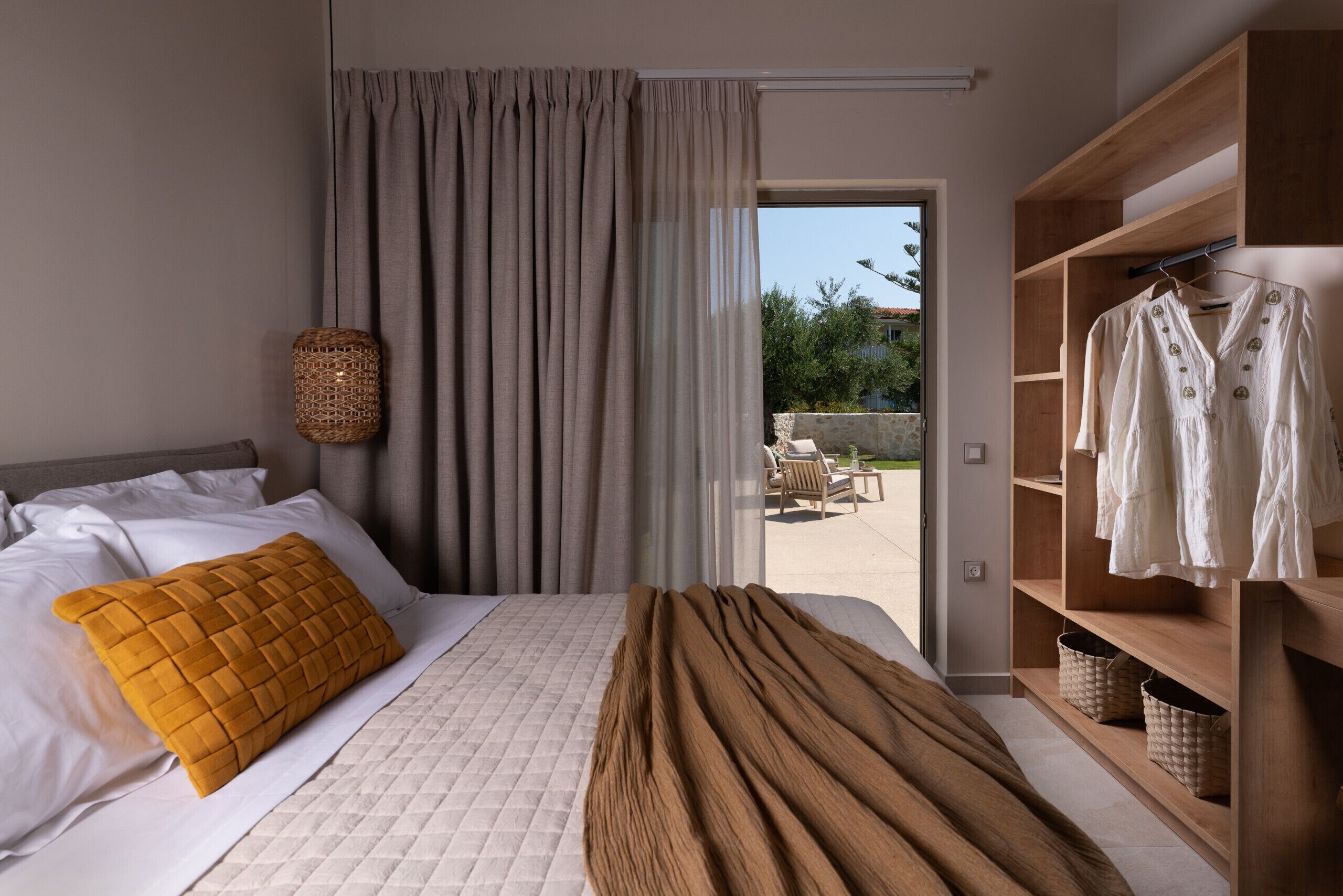 Una camera da letto con un letto, un'ampia finestra con tende, un armadio in legno e vista sull'esterno.