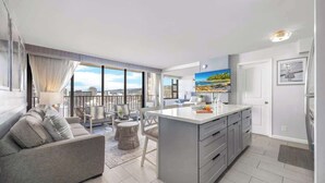 A modern apartment with a balcony, a dining area, a kitchen, and a living room. - Ocean-view condo w/ lanai & sweeping views (Honolulu)