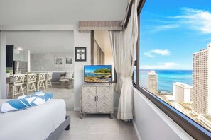 Ein Hotelzimmer mit Bett, Fernseher, Essbereich und Meerblick.