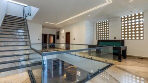 A modern interior with a glass railing, a pool table, and a staircase. - Heartland Ganga View Villa Jacuzzi &lift (Rishikesh)