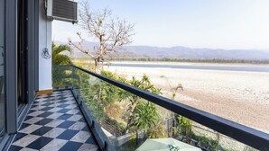 A balcony with a checkered floor, overlooking a river and mountains. - Heartland Ganga View Villa Jacuzzi &lift (Rishikesh)