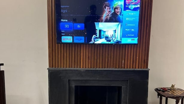 A flat-screen TV mounted on a wooden wall above a fireplace. - Heartland Ganga View Villa Jacuzzi &lift (Rishikesh)